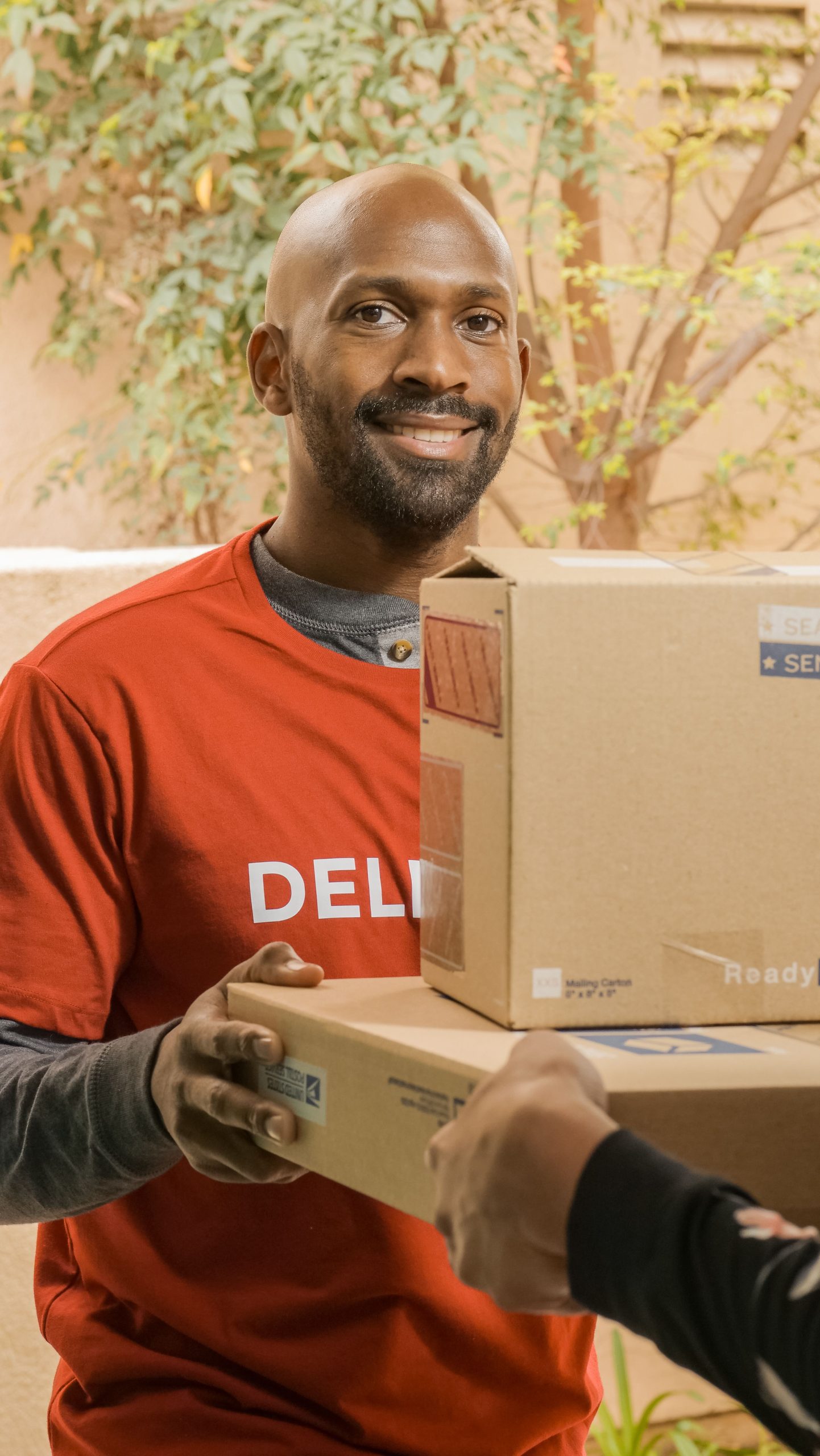 About Courier wearing a uniform delivering packages with a smile outdoors on a sunny day.
