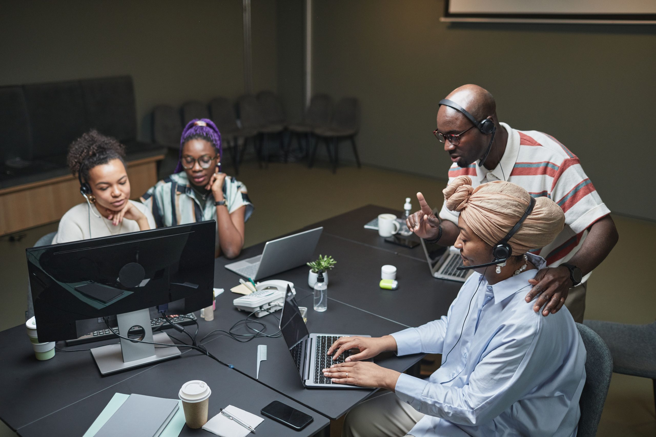 About Team of coworkers in an office call center collaborating and using laptops.